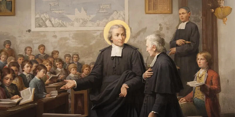 A classical painting depicting a man with a halo, wearing black robes, teaching in a classroom as young boys sit at desks and read.